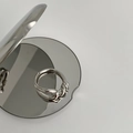 Dettaglio di un anello a nodo argento minimalista con doppia fascia su uno specchio - Stile a Nodo / Argento