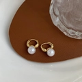 Detailopname van gouden oorringen met witte parels op leer en glas decoratie display - Goud met kleine parel