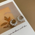 Detalle de pendientes de aro trenzados con perlas blancas sobre tarjeta artística - Plateado
