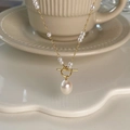 Detail of elegant gold OT toggle necklace with natural pearls on a white ceramic dish - Pearl OT Buckle Lock Necklace