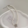 Detail einer Perlenkette mit diamantbesetztem Blumenanhänger auf einem Steintablett - Silber Hochglanz Perle Blume Halskette
