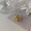 Détail de la bague fleur dorée avec zircone cubique sur un fond minimaliste texturé - Ouvert Réglable / Doré