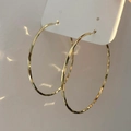 Primer plano de pendientes de aro dorados con una textura única de metal martillado - 5cm / Dorado