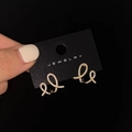 Boucles d'oreilles nœuds dorés serties de zircons sur carte de présentation - Doré