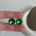Close-up of vintage emerald glass earrings with golden wheat pattern borders - Emerald