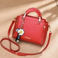 Bolso de cuero rojo con logo dorado y remaches de corazón visto desde un ángulo de 45 grados - Rojo