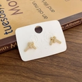 Nahaufnahme goldener Knotenknoten-Ohrringe mit Zirkonia auf Vintage-Buch-Hintergrund - Gold Super Glänzender Zirkon Geknotet (Echtgold Vergoldet)