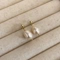 Close-up of Baroque freshwater pearl earrings with gold-plated studs on a velvet tray - Gold/Off-white