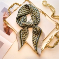 Detailed shot of a geometric silk scarf tied in a bow on a vintage gold relief tray - 70x70cm / Blue Color Block Geometric (FJ567-3)