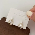 Detailed view of geometric gold stud earrings with elegant white pearls and zircon crystals - Gold
