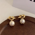 Macro-opname van vintage gouden knoopoorbellen met elegante parelhanger - Stud oorbellen / Gouden Knoop Witte Parel