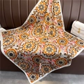 Close-up of retro floral mandala silk scarf draped on a leather sofa with elegant details - Bright Orange Mandala (FN82-1)