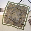 Detail of green paisley silk scarf with intricate vintage pattern on a soft beige carpet - Dark Green Ginger (FJ537-6)