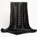 Dettaglio di un foulard in raso nero che mostra la lucentezza della seta e il logo elegante - 90x90cm / Nero