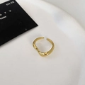 Nahaufnahme eines doppelschichtigen gewellten Goldrings auf einem weißen Display - Gold
