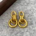 Detail of matte gold geometric linked hoops on grey fabric with minimalist vintage style - Gold Matte Circle Studs