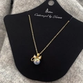 Detalle de perla de sirena con lazo dorado y circón en una tarjeta de presentación - Collar de Zirconia con Lazo de Perlas de Sirena Dorada