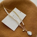 Dettaglio del ciondolo a cuore e della perla barocca su una catena placcata oro - Collana con perle d'acqua dolce giuntate con ciondolo a cuore