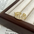Detailed shot of crown ring with marquise zircon and pearls on wooden jewelry display - Gold Crown Zircon Shell Pearl Style