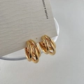 Makroaufnahme von dreischichtigen Goldohrringen auf minimalistischer Displaykarte - Gold