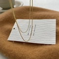Detail einer goldenen doppellagigen Halskette mit Schlangenkette auf warmer Textur - Goldene Doppelschichtige Einfache Kette