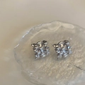 Close-up of square woven metal stud earrings with irregular edges on a glass tray - Silver (Genuine Silver Plated)