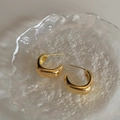 Detailopname van minimalistische gouden geometrische U-oorbellen op matglas - Goud / Oorbellenpost