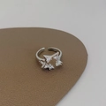Makro-Detail des offenen Sternrings mit Zirkonia-Steinen auf braunem Lederhintergrund - Silber