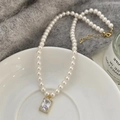 Dettaglio di collana di perle con ciondolo in zircone rettangolare su piatto bianco - Collana Perla Bianca Zircone Trasparente