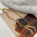 Close-up van dubbellaagse gouden slang- en Figarokettingen op grijs breigoed - Goud