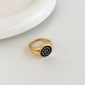 Close-up of golden adjustable ring with black enamel inlay and concentric circle pattern - Gold Black Round Style