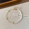 Detail of half pearl and gold chain bracelet with zircon stone and handmade fabric tag - Gold