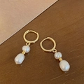 Detalle de pendientes de aro dorados con perlas barrocas sobre superficie de madera - Perla Natural Dorada