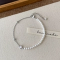 Close-up of pearl and silver chain bracelet with lobster clasp on beige fabric - Silver