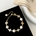 Detail of gold pearl bracelet with clover charms on black velvet display stand - Gold