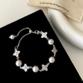 Macro detail of elegant silver bracelet with grey pearls and zircon clover charms - Silver
