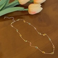Dettaglio collana dorata con gemme colorate quadrate su sfondo in legno rustico - Collana di giunzione in zirconia quadrata multicolore