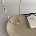 Close-up of elegant gold beaded necklace with white pearls on a ceramic tray - Gold