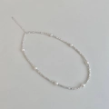 Macro shot of silver beaded necklace with seven round pearls and lobster clasp closure - Interspaced White Pearl Style