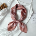 Nahaufnahme eines rosa Seidenschals mit Paisley-Muster als Schleife auf Satin - Altrosa