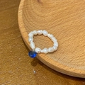 Detail of freshwater pearl beaded ring featuring a blue gemstone pendant on a wooden tray - Blue Zirconia Freshwater Pearl Ring