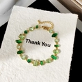 Vista detallada de pulsera dorada con circonitas verdes de varias formas y cierre de langosta - Pulsera Chapada en Oro con Circonita Verde Fresca