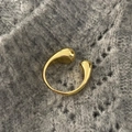 Macro detail of gold teardrop open ring on textured grey knit background - Gold