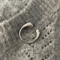Macro view of minimalist silver adjustable ring with drop-shaped ends on knit fabric - Silver