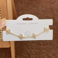 Elegante bracciale a quadrifoglio dorato con inserti bianchi su espositore - Oro