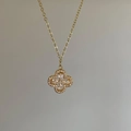 Macro detail van vergulde klaver hanger met peer-geslepen zirkonia en fijne kruisjesketting - Goud