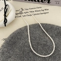 Close-up of white pearl necklace with silver clasp on a textured fabric background - 4mm White Style