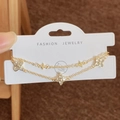 Double-layered golden clover bracelet with shimmering crystal inserts on a jewelry card - Gold