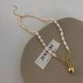 Close-up of baroque pearl necklace with gold heart pendant on a rustic ceramic tray - Heart Pendant Freshwater Pearl Splicing Style (B-275)