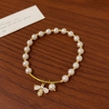 Detailed macro view of pearl bracelet featuring a gold crystal-encrusted bee charm - Bee Pendant Style